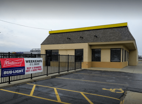 A building with a yellow roof and a sign advertising Bud Light and a weekend promotion for kids' meals.