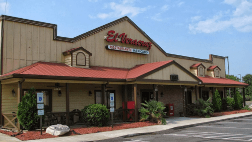 Exterior of El Veracruz, a Mexican restaurant, featuring a tan building with a red roof and landscaped entrance.