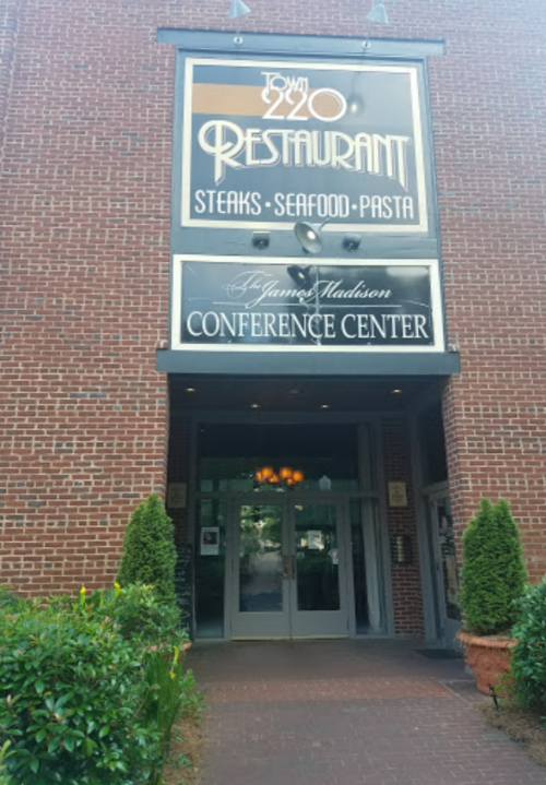 Entrance of 220 Restaurant featuring a sign for steaks, seafood, and pasta, alongside the James Madison Conference Center.