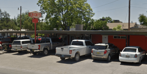 A row of parked vehicles in front of a building with a sign that reads "Becky's" on a sunny day.