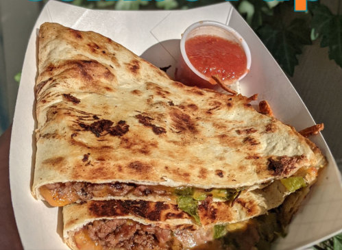 A golden-brown quesadilla filled with beef and peppers, served with a side of salsa.