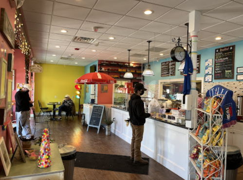 A colorful café interior with a counter, seating area, and customers. Bright walls and decor create a welcoming atmosphere.