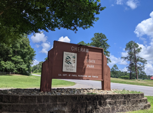 Sign for Cheraw State Park in South Carolina, surrounded by greenery and blue skies.