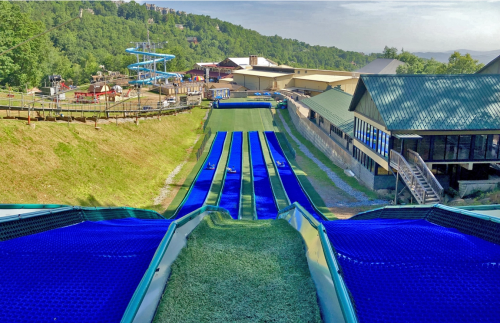 A view of a water slide park with multiple blue slides and a scenic green hillside in the background.
