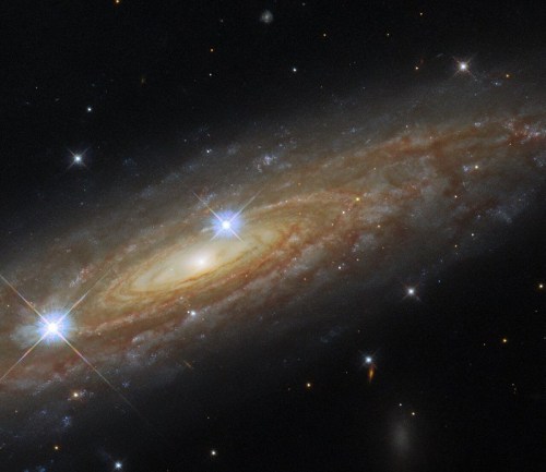 A stunning spiral galaxy with bright stars and swirling dust, set against a backdrop of distant galaxies and stars.