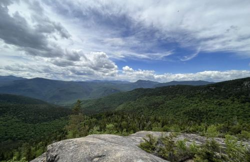 A panoramic view of lush green mountains under a partly cloudy sky.