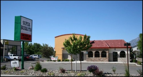 A Mexican restaurant named "Super Burrito" with a colorful exterior and a sign in front, surrounded by landscaping.