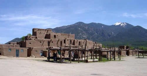 A traditional adobe village with a mountainous backdrop under a clear blue sky.