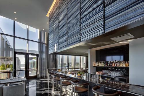 Modern bar interior with sleek design, large windows, and a stylish counter displaying various drinks.