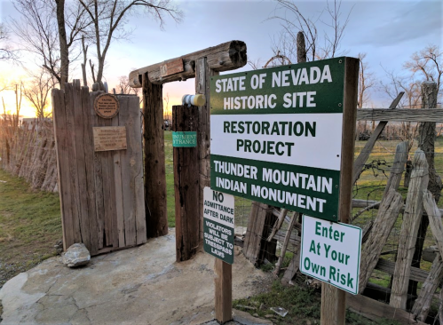 Signage at the entrance of the Thunder Mountain Indian Monument, a historic site in Nevada, with restoration project details.