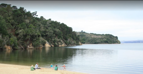 A serene beach scene with a family playing by the water, surrounded by lush greenery and calm waters.