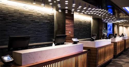 Modern reception area with sleek counters, multiple check-in stations, and stylish pendant lighting.