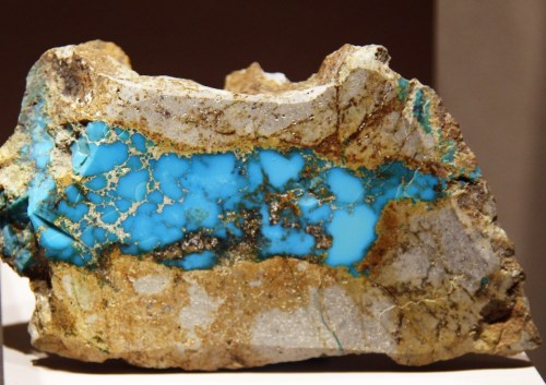 A rock featuring vibrant blue turquoise veins and a textured, earthy surface.