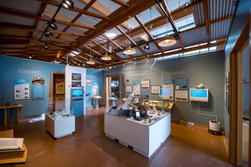 A modern museum exhibit featuring informational panels, displays, and artifacts in a well-lit, open space.