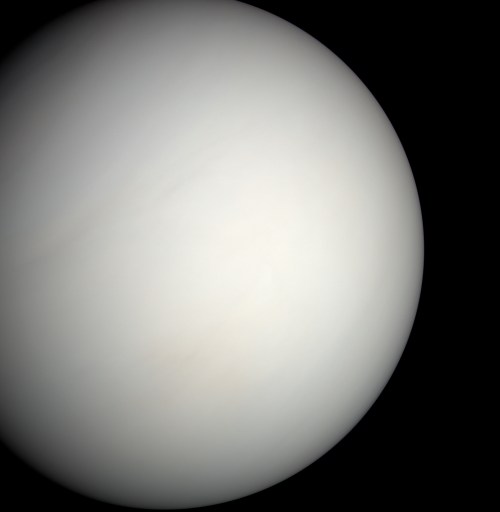 A close-up view of a pale, featureless planet, likely representing a gas giant in space.