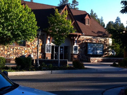 A stone building with a sloped roof, surrounded by trees, featuring a marquee sign and a lamp post in front.