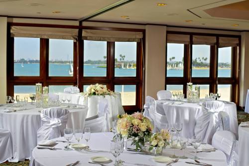 Elegant dining setup with white tablecloths and floral centerpieces, overlooking a scenic waterfront view.