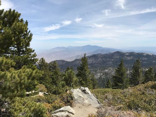 A scenic mountain view with lush green trees and rocky terrain under a partly cloudy sky.