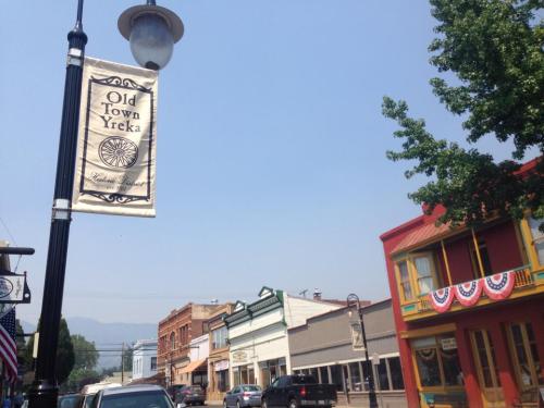 Street view of Old Town Yreka, featuring banners, colorful buildings, and a clear sky.