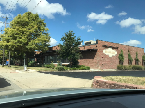 A brick building with a sign reading "Ida Claire," surrounded by trees and a clear blue sky.