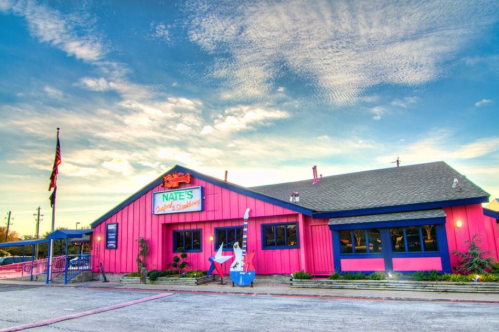 A colorful restaurant building with a pink exterior, featuring a sign that reads "Nate's Seafood & Steakhouse."
