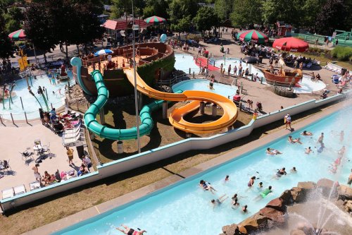 A vibrant water park featuring slides, a lazy river, and families enjoying the attractions on a sunny day.