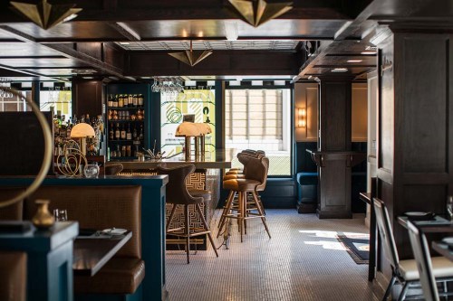 A stylish restaurant interior featuring a bar, elegant seating, and warm lighting, creating a cozy atmosphere.