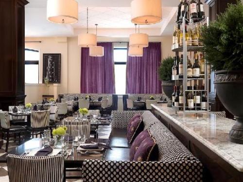 Elegant restaurant interior featuring striped seating, purple curtains, and a wine display against a marble bar.
