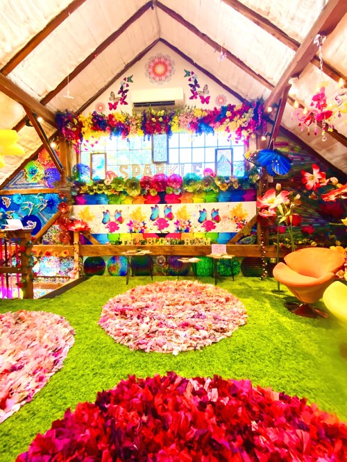 Colorful, flower-themed interior with vibrant decorations, green grass-like flooring, and bright seating in a cozy attic space.