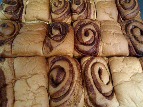 A close-up of freshly baked cinnamon rolls arranged in a grid pattern, showcasing their swirled tops.