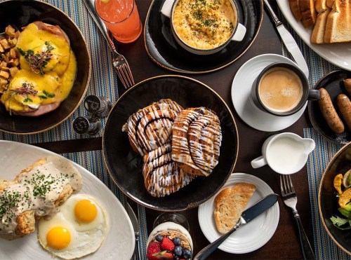 A delicious breakfast spread featuring eggs, pastries, coffee, and fruit on a table.