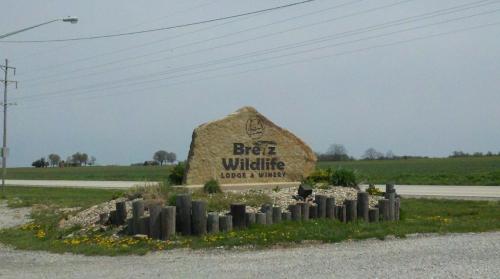 Sign for Breitz Wildlife Lodge & Winery, featuring a large stone and decorative landscaping along a rural road.