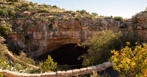 Entrance to Carlsbad Caverns in NM showing sandstone exterior and a footbridge.