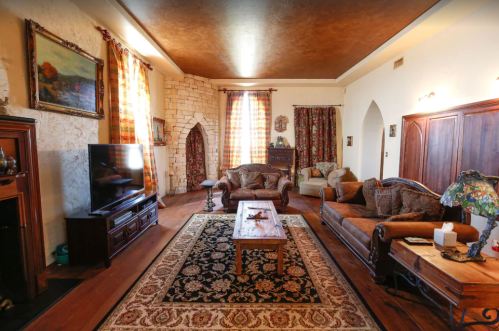 Cozy living room with a wooden coffee table, plush sofas, a TV, and decorative curtains in warm tones.