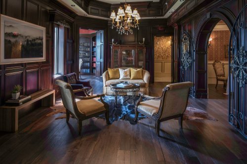 Luxurious living room with dark wood paneling, elegant furniture, a chandelier, and a cozy atmosphere.