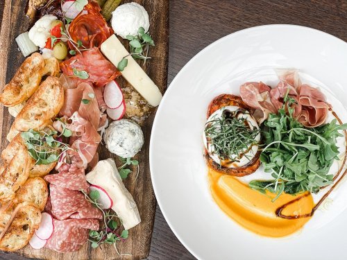 A charcuterie board with meats, cheeses, and garnishes alongside a plate of prosciutto, greens, and a creamy dish.