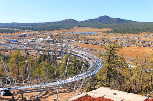 A scenic view of a roller coaster track winding through a mountainous landscape with a small town below.