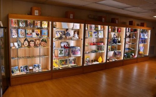 Display cases filled with various collectibles, including photos, toys, and memorabilia, in a well-lit room.