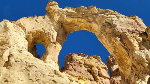 Natural rock formations with arches against a clear blue sky.