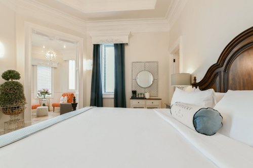 A cozy hotel room featuring a large bed, elegant decor, and a sitting area with natural light.