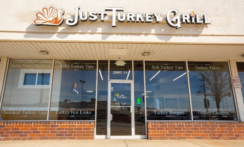 Exterior of Just Turkey Grill, featuring a menu display with various turkey dishes and a welcoming storefront.