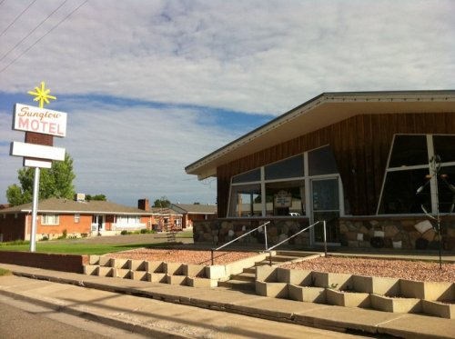 Exterior of Sunflower Motel with a retro sign, featuring a stone facade and a clear sky in the background.