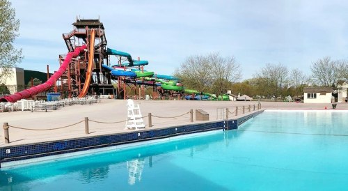 A water park featuring colorful slides and a clear swimming pool under a blue sky.