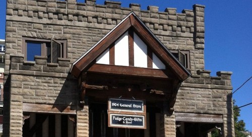 A stone building resembling a castle, featuring a sign for a general store and a clear blue sky above.