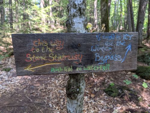 Wooden sign in a forest directing to the Stone Stairway and Wreck Bypass, with colorful arrows indicating paths.