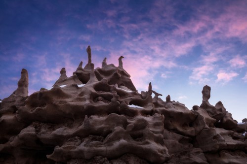 Rock formations with unique shapes against a colorful sky at dusk.