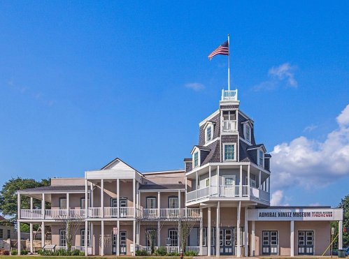 Historic building of the Admiral Nimitz Museum with a flag atop, featuring a multi-level design and blue sky backdrop.