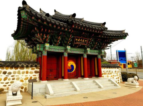 A traditional Korean-style pavilion with ornate roof and colorful decorations, set against a stone wall.