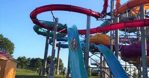 A water slide at an amusement park with colorful tubes and a clear blue sky in the background.
