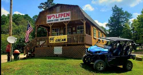 A wooden country store with a sign reading "Wolfpen," featuring an ice cream banner and a blue ATV parked outside.